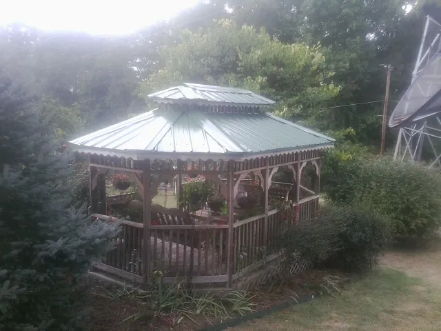 Green metal roof on a backyard gazebo surrounded by garden beds in Gibson