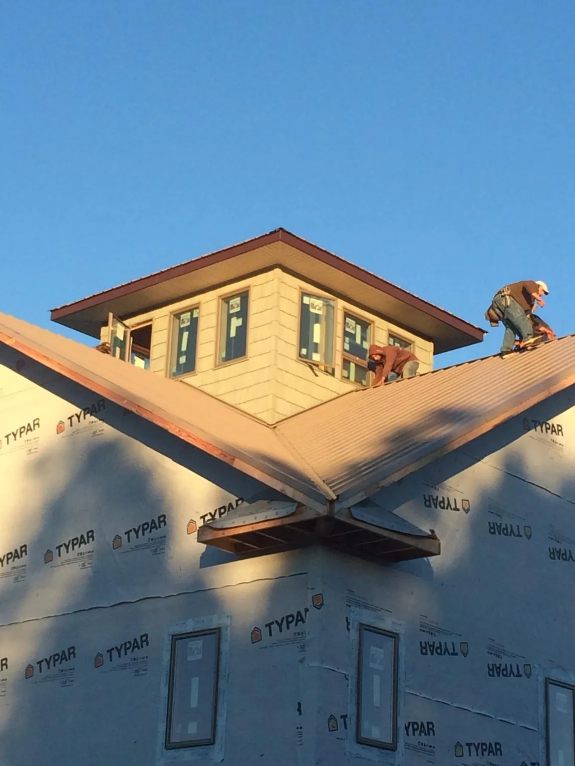 Roofers working around a rooftop cupola on a new metal roof at sunset — Roof Waterproofing in Gibson by Roofing Brothers